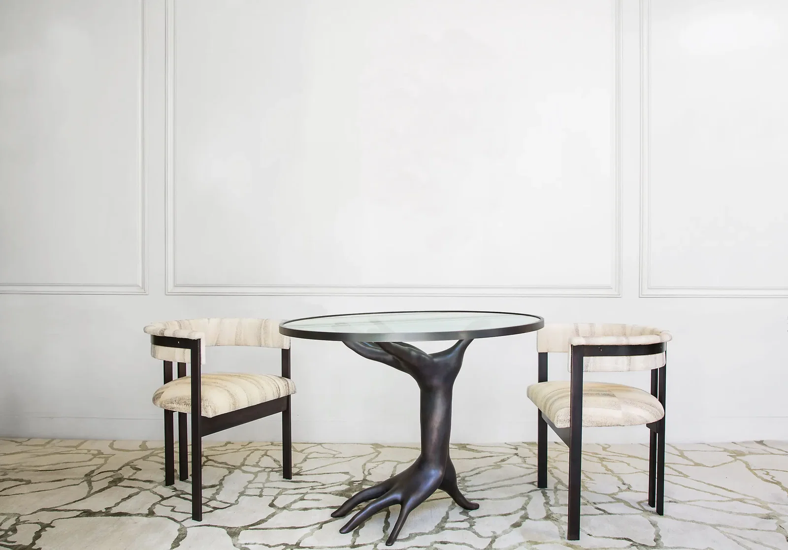 Dichotomy table in cast bronze and glass with upholstered Elliott chairs in solid bronze