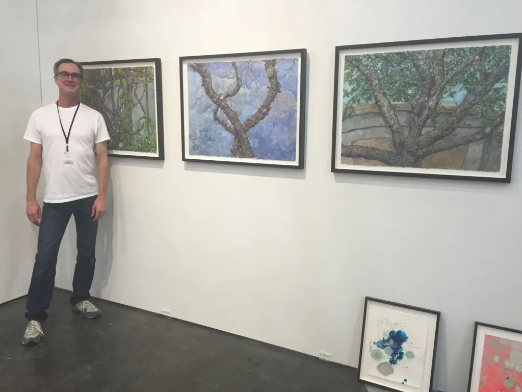 Inman Gallery goes with a conceptual landscape theme. Director Patrick Reynolds poses with a wall of Beth Secor paintings.