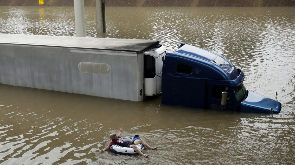 Man floats on the freeway, after helping the driver of a submerged truck escape to safety. (Photo by Charlie Riedel / AP) 