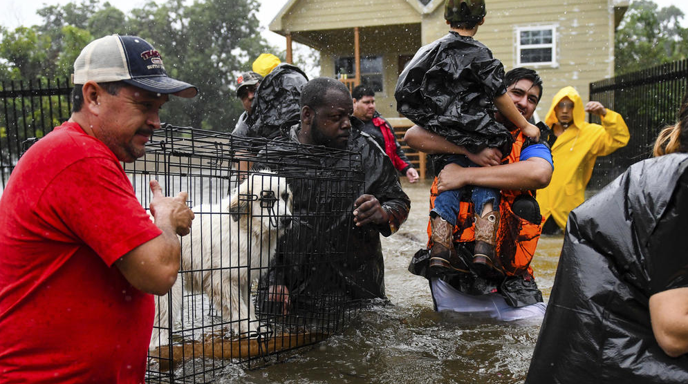 First responders and volunteers help residents evacuate rising flood waters. (Photo by Scott Clause / he Daily Advertiser via AP)