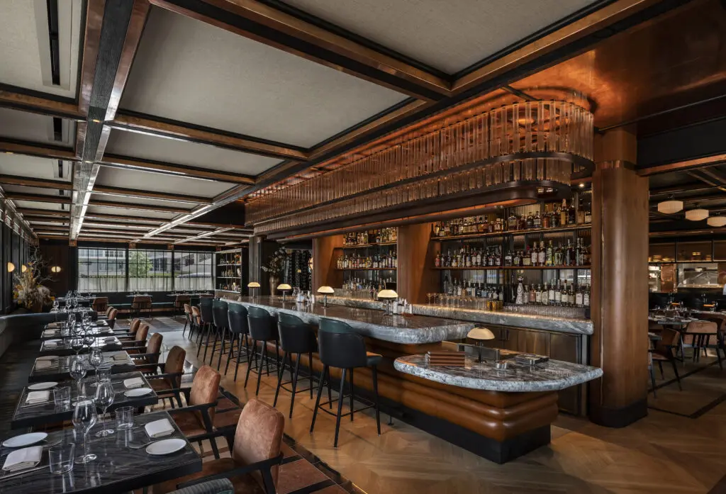 Andiron's dine-in bar area is covered with a smoky-looking Cippolino marble, lit overhead by a 28-foot-long custom chandelier made with 250 tubes of light. (Photo by Julie Soefer)