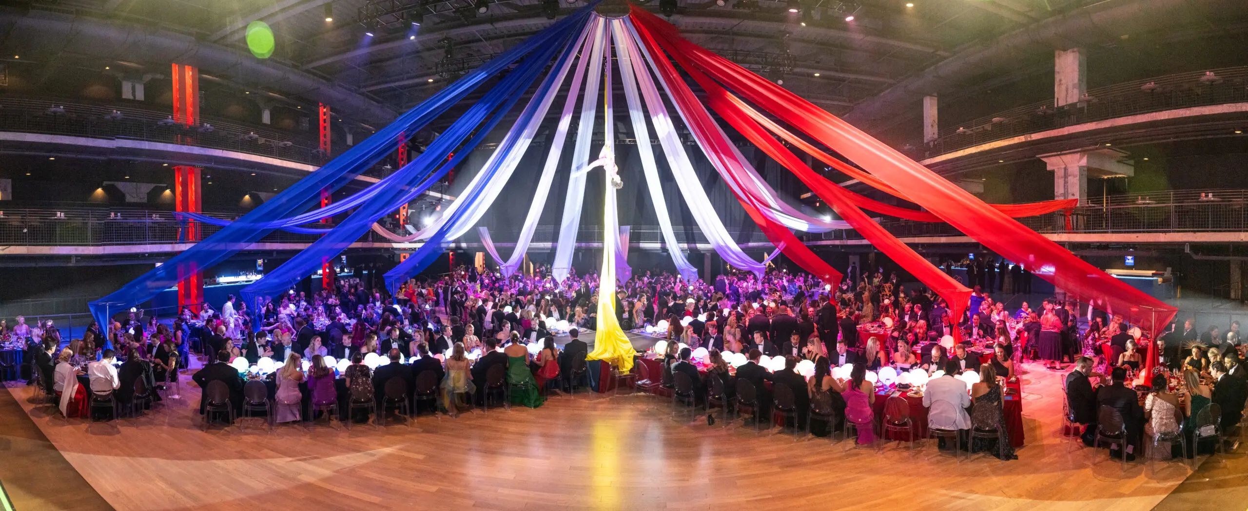 An aerialist performs overhead as guests dine at the Children's Fund gala, 'An Evening of Mystère,' held at the 713 Music Hall (Photo by Wilson Parish)