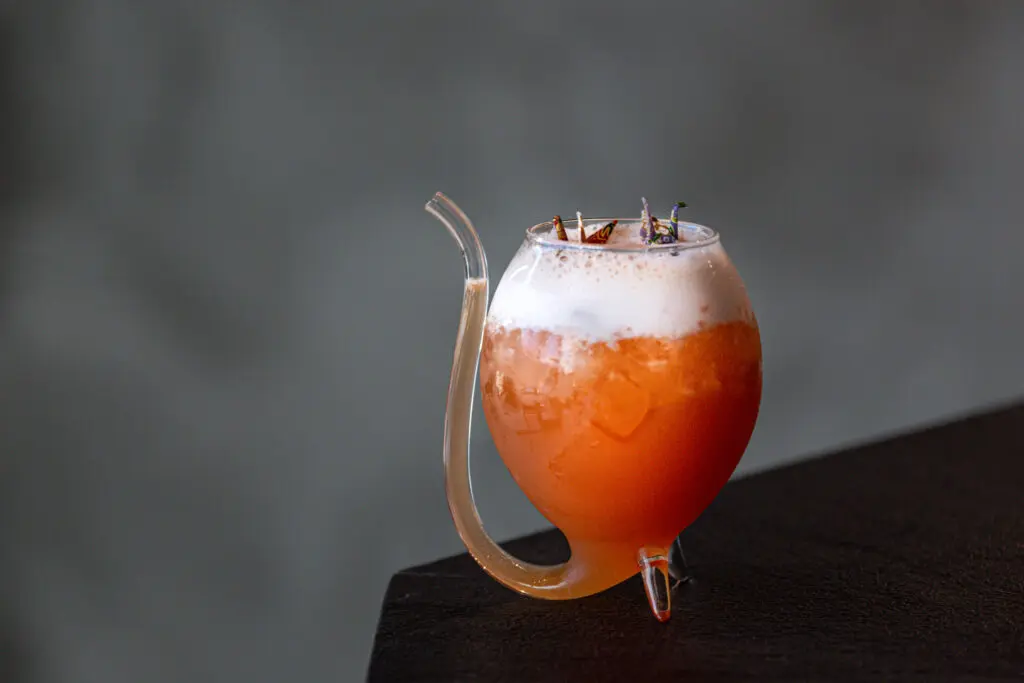 Sneak into Hidden Bar where bartender Hao Ma is mixing up drinks like their signature paper crane ($16) a blend of bourbon, rum, Aperol, pineapple, and coconut juices served in a crane-shaped cocktail glass. (Photo by Jenn Duncan)