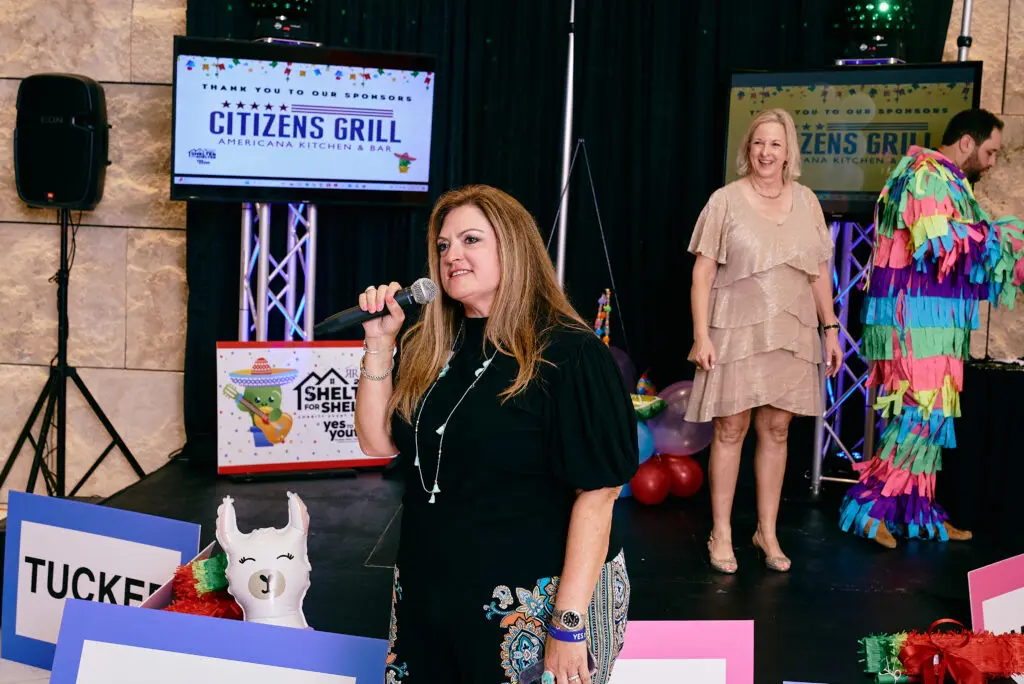 Michele Kooken, CEO of YES to YOUTH, addresses the crowd as Marlys Mulkey looks on.