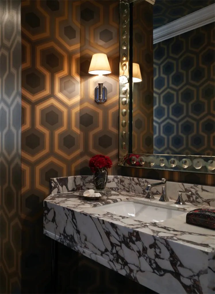 A moody powder bath with Cole &. Son geometric wallpaper. Vintage Venetian glass mirror. Custom marble vanity, silver accessories from Well Sourced. (Photo by Pär Bengtsson)
