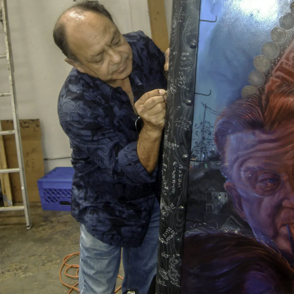 In this 2007 photo, Cheech Marin signs Vincent Valdez's "El Chavez Ravine" in the artist's studio, then located in Boyle Heights. Commissioned by Ry Cooder in 2004, the piece features a 1953 Chevy ice cream truck transformed by the Dukes Car Club in Los Angeles. (Photo by Melissa Richardson Banks)