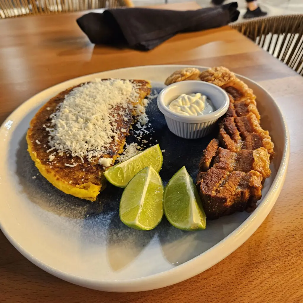 The cachapa at Big Yummy Grill House & Bar is a must-try: thick cornmeal cakes filled with queso de mano, topped with queso fresco, and served with a crispy chicharrón and lime. (Photo by Edward Brown)