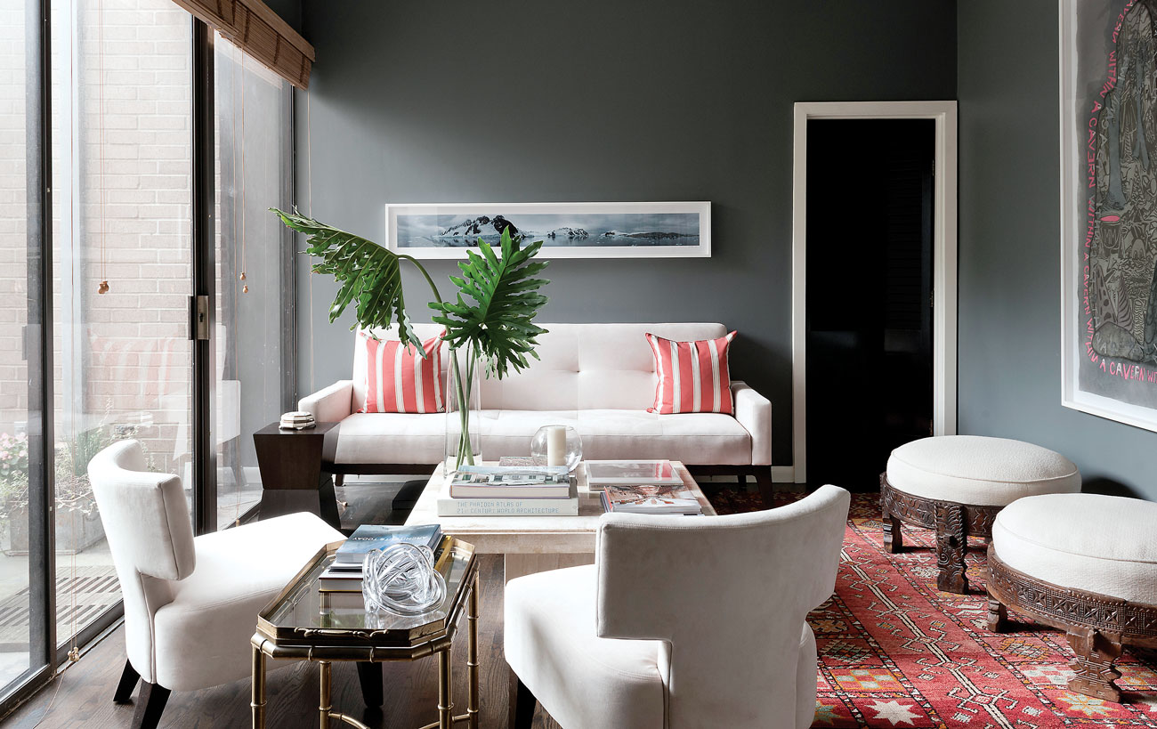 In the den, the low seating is from West Elm. Circular carved wooden stools from Indian mills, once used to grind grain, have been repurposed as ottomans and covered in Knoll fabric. A Moroccan rug and Libbie Masterson’s Antarctica 360° (artist proof), 2008, add to the exoticism of the room.