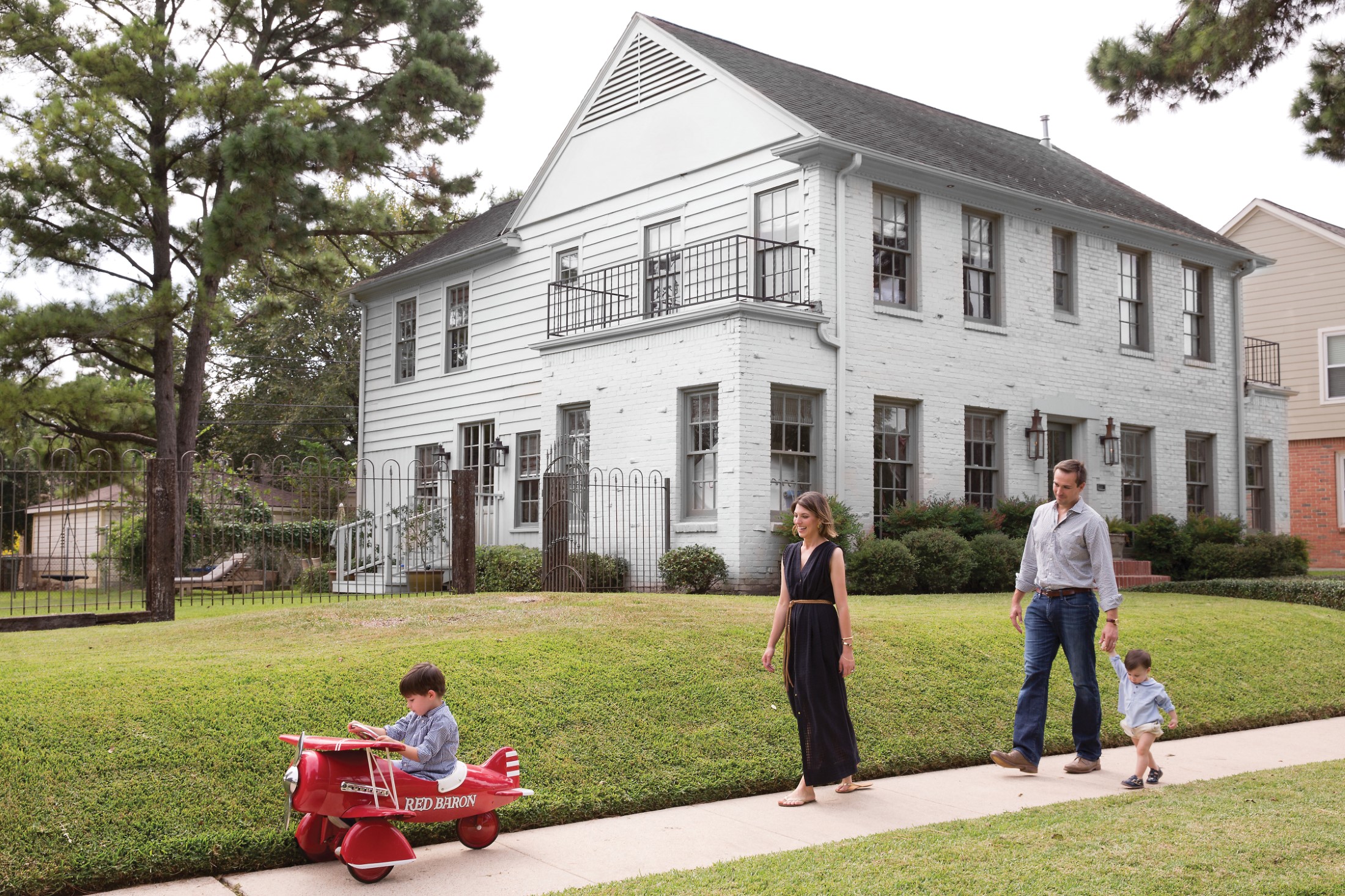 Courtney Barton, dressed in Mirth Caftans, with husband JJ and sons Ory and Theo in front of their 1946 Idylwood home.