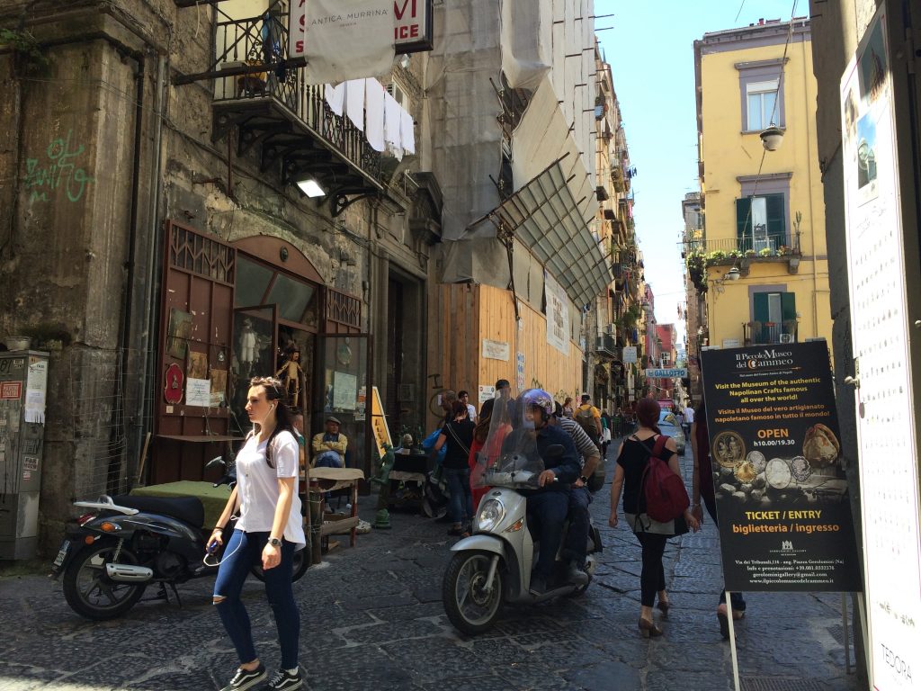 Pedestrians and Vespas on busy narrow streets.