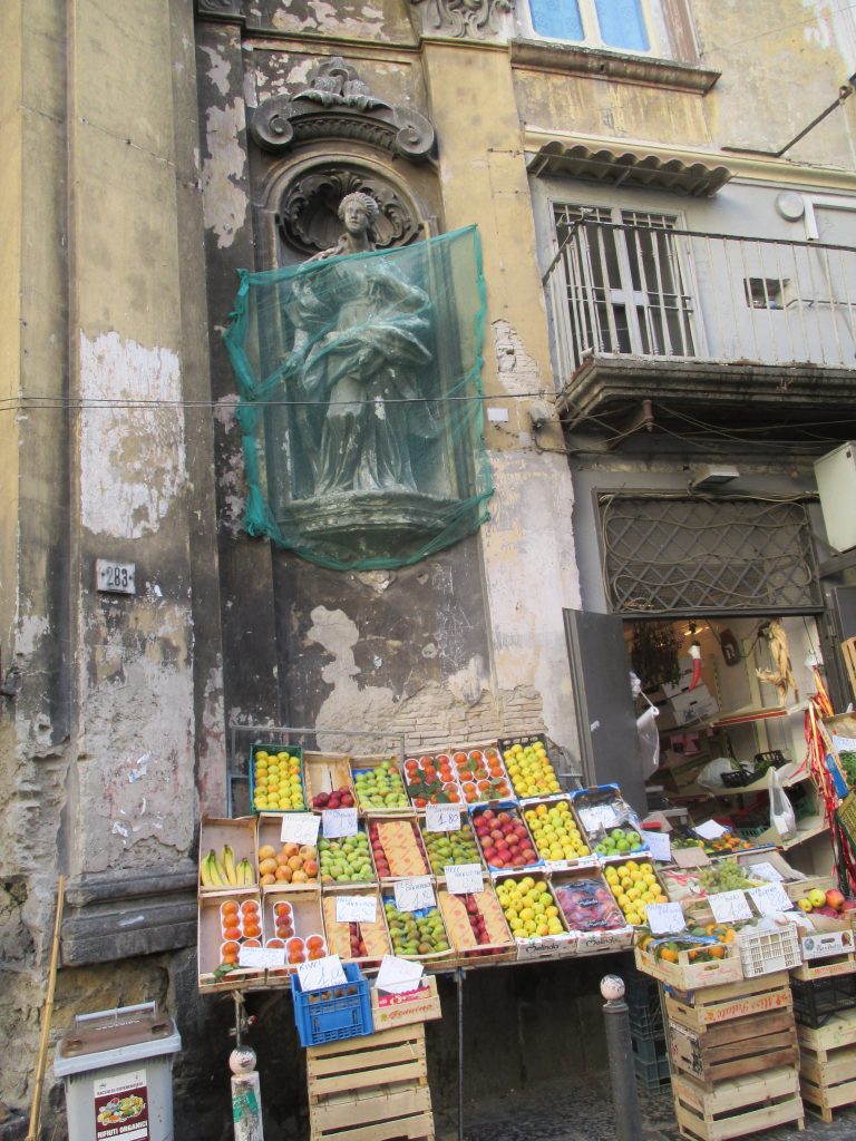 Neopolitan fruitstand beneath a crumbling angel in 2013. Today, the space has been taken over by restoration. 