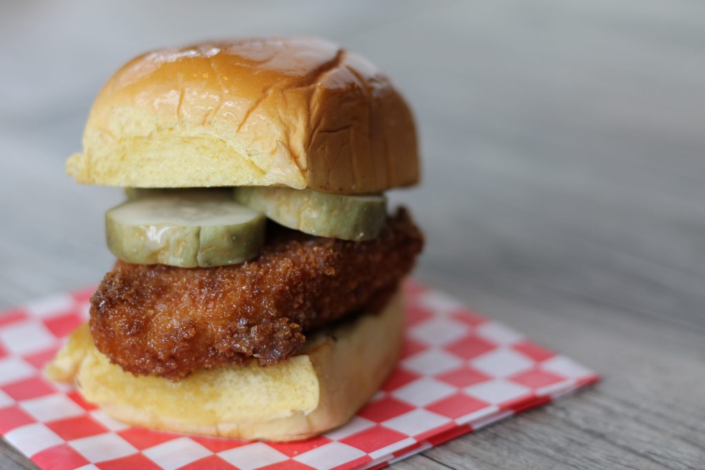 The chicken sandwich is topped with agave butter and sliced pickles. 