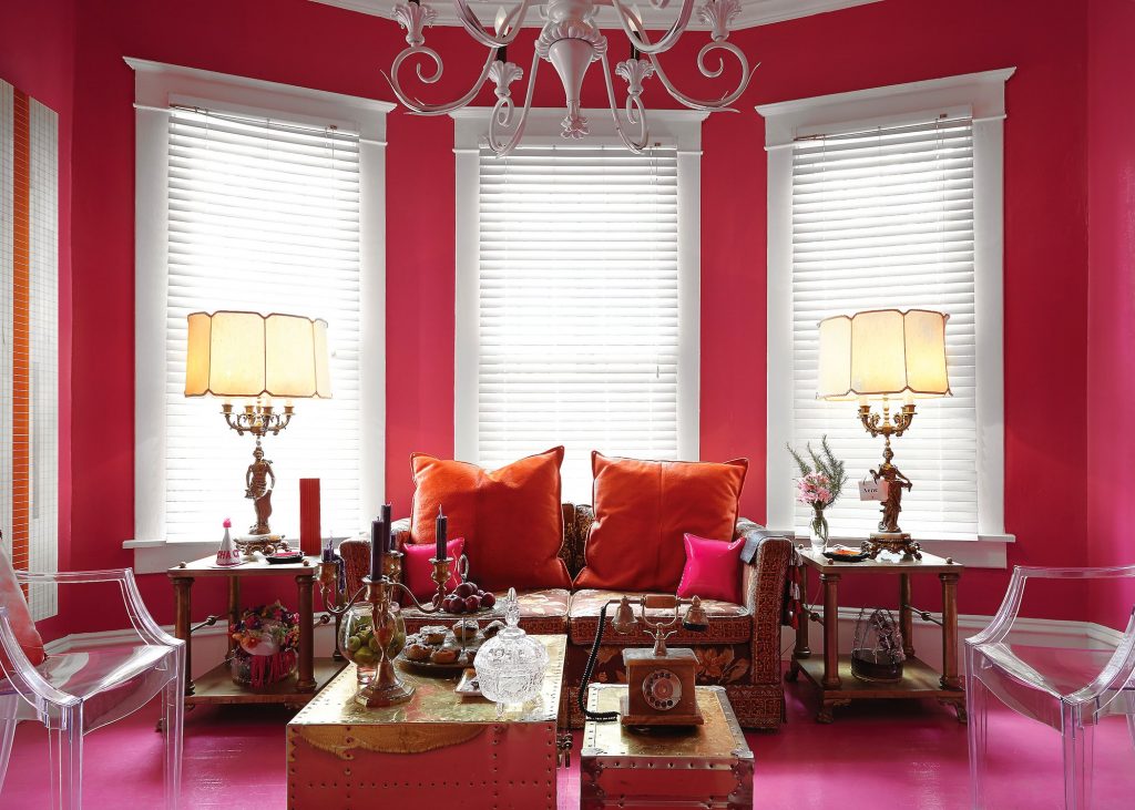 The sofa in the living room was discovered by Sam Saladino and re-covered in pink floral fabric as a play on Diana Vreeland's "garden in hell." Vintage lamps and tables. Dan & Joseph pink and orange patent-leather pillows, $175 to $595.