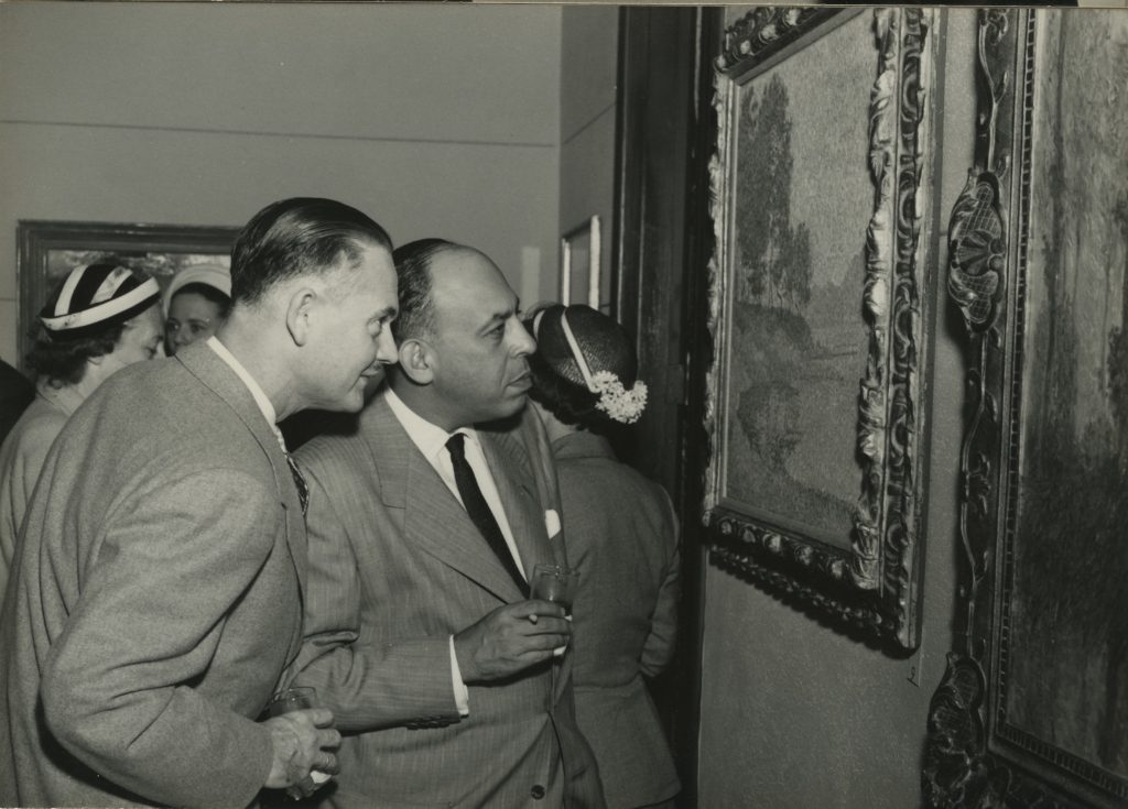 Stanley Marcus, right, studies at Paul Signac landscape at the opening of Betty McLean Gallery, 1951.