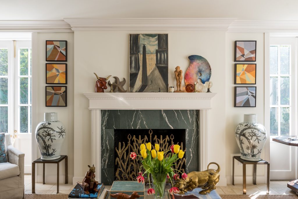 In the main-house living room is a series of paintings by Palm Beach artist Michelle Feder. Over the mantel, vintage painting found in France. Hammered-metal and stone side tables from Mecox.