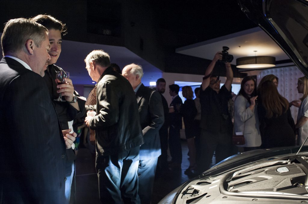 The crowd admires the sleek Porsche Panamera.