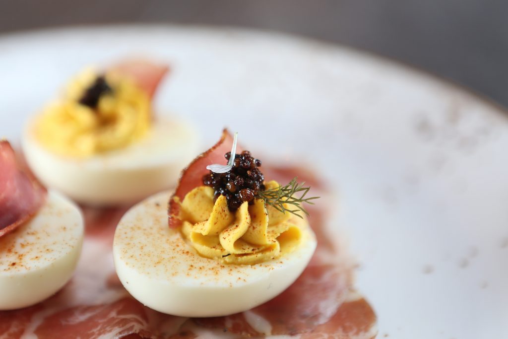 Start your meal with the at Bacon Bros. with the Devil's Dust Eggs topped with tasso ham and mustard seed. 