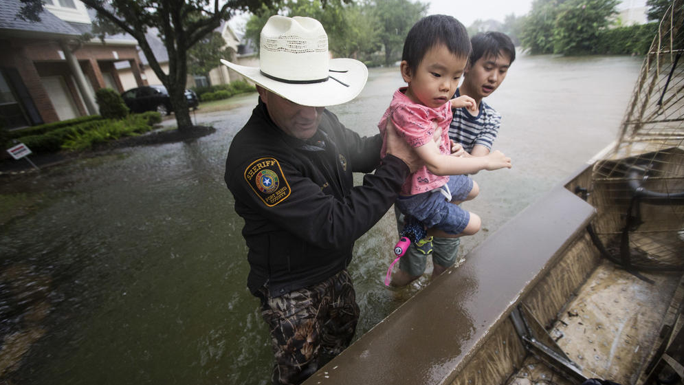 Fort Bend County Sheriff Troy Nehls and Lucas Wu lift Ethan Wu into an airboat. (Photo by Brett Coomer / Houston Chronicle) 