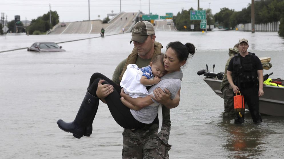 Houston police SWAT Officer Daryl Hudeck carries Catherine Pham and her 13-month-old son Aiden to safety. (Photo by David J. Phillip / Associated Press) 