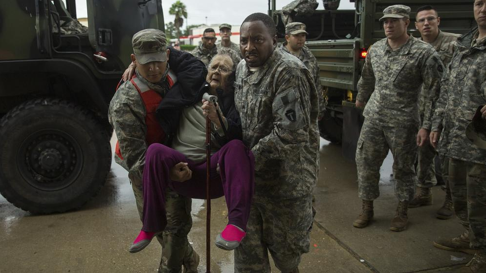 Texas Army National Guard members Sergio Esquivel and Ernest Barmore rescue 81-year-old Ramona Bennett from Pine Forest Village neighborhood. (Photo by Erich Schlegel / Getty Images) 