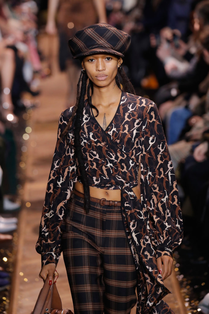 Model Adesuwa Aighewi walks the runway in a Michael Kors camouflage wrap blouse, checked pants and matching cap. (Photo by JP Yim/Getty Images for Michael Kors)