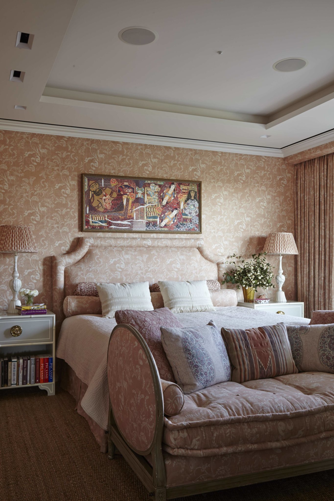In the master bedroom, walls and headboard are upholstered in Pandora and lampshades in Jaisalmer, both by Lisa Fine Textiles. Pinwheel night tables from the Dorothy Draper Collection by Carleton Varney for Kindel. The painting is by the Iranian artist Afsoon.