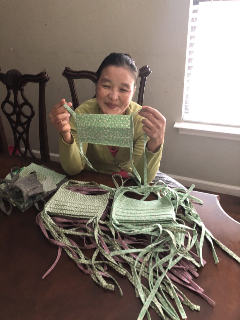 A refugee artisan holds up a mask she has made.