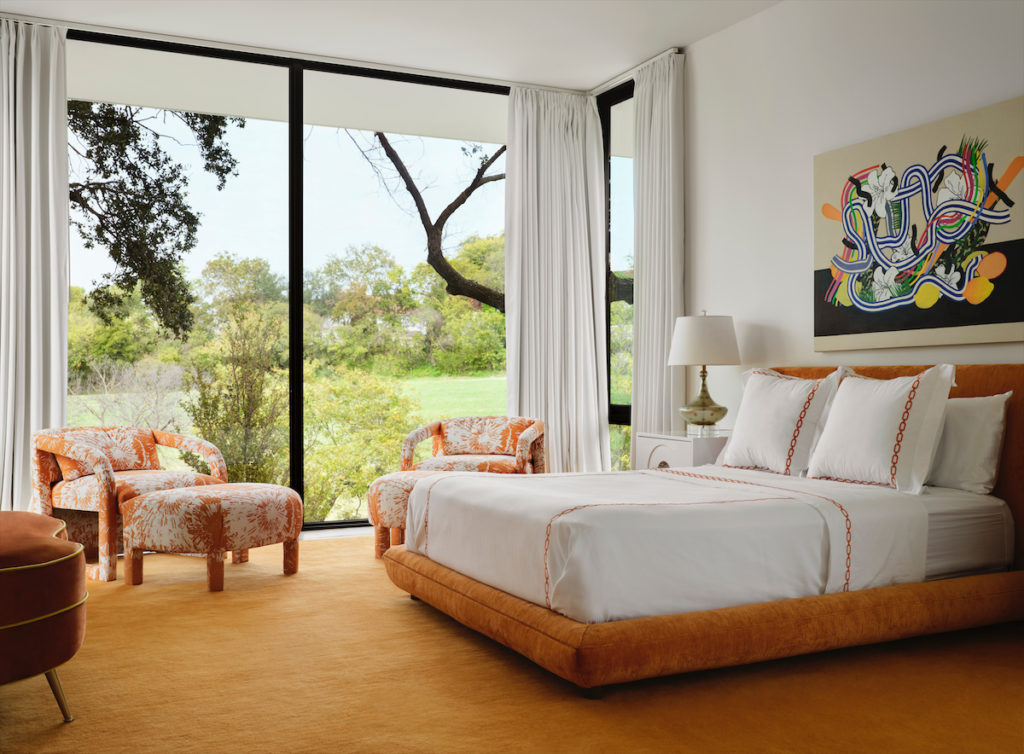 In a guest bedroom, the custom bed, chairs, and ottomans are covered in various orange textiles by Calvin Fabrics. Hamburg House linens from George Cameron Nash. Custom rug from The Rug Company. Stephen D'Onofrio artwork from Gallerie Urbane. (Photo by Lisa Petrole)