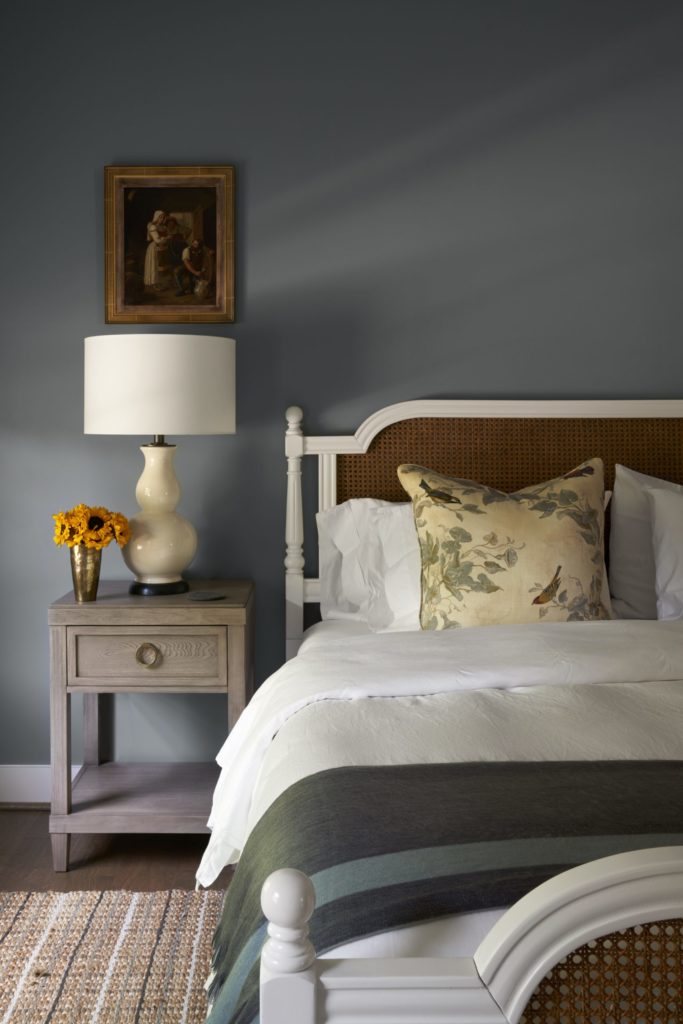Bedroom walls are painted Sherwin Williams Cadet Grey. Wicker bed from Macy's. Lamp from Memorial Traders, Houston. Painting from Lewis & Maese Antiques and Auctions. Brass vase from Courtney Barton Round Top. Alpaca throw on bed from Manos De Sur at Round Top Antiques & Design Center and at The Compound during shows. (Photo by Pär Bengtsson)
