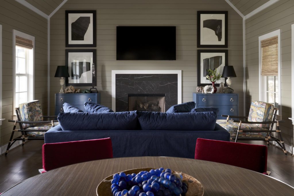 In one of the great rooms, Knoll chairs in red mohair started the inspiration for this bungalow's modern mix, which includes a pair of Article rattan chairs and a linen slipcovered sofa from Grandin Road. Blue glass balls from Paul Michael, Round Top. Abstract black and white photographs of horses by photographer Steven Klein. (Photo by Pär Bengtsson)