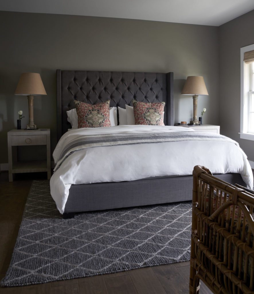 In a bedroom is a tufted flannel bed and glazed linen nightstands. Antique lamps from Lewis & Maese Antiques
and Auctions. Walls are Sherwin Williams' Cadet Gray. (Photo by Pär Bengtsson)