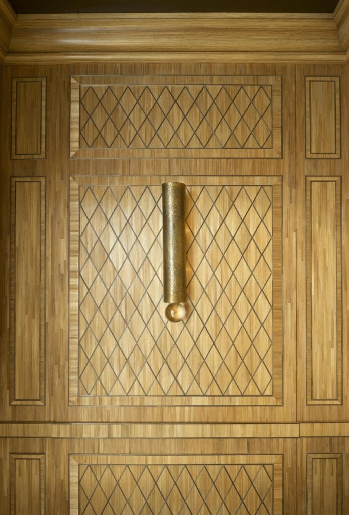 In a Manhattan apartment, straw marquetry panel from Feau Boiseries, inspired by the work of Jean-Michel Frank. Tube wall lamp by Hervé Van Der Straeten, 2000. (Photo by Jacques Pepion)