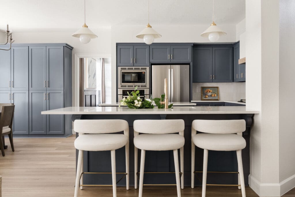 The kitchen’s bar seating offers a casual dining option and highlights the updated cabinetry, lighting and soft blue palette. (Photo by Madeleine Harper)