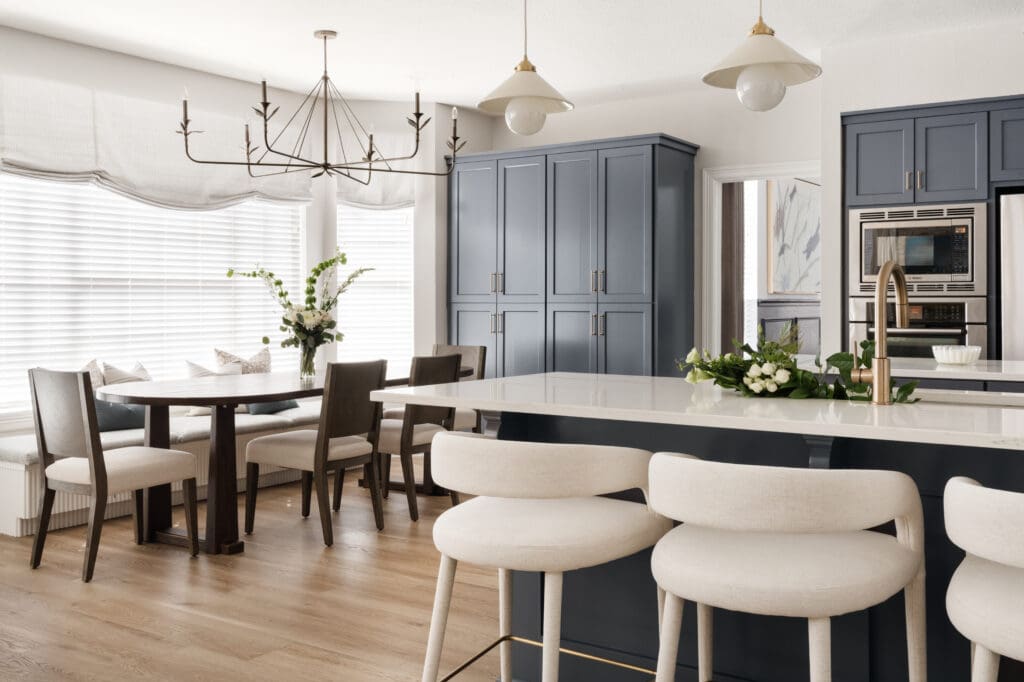 The kitchen’s bar seating flows into the dining area, where a warm wood table and soft palette create a welcoming space. (Photo by Madeleine Harper)