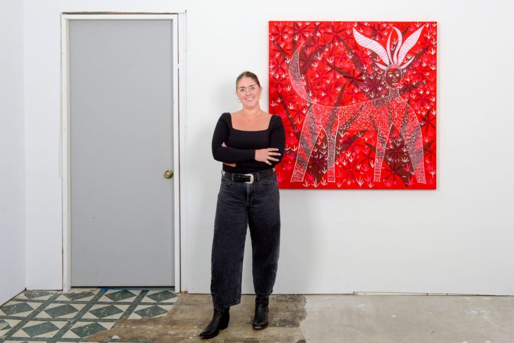 Gallerist Laura Burton poses next to Gerardo Rosales' "Faun," 2025, one of the canvases that are calling cards of the Venezuelan-born Houston-based painter's latest show at her eponymous gallery. Image courtesy the artist and Laura (the gallery), photo © Graham W Bell. 