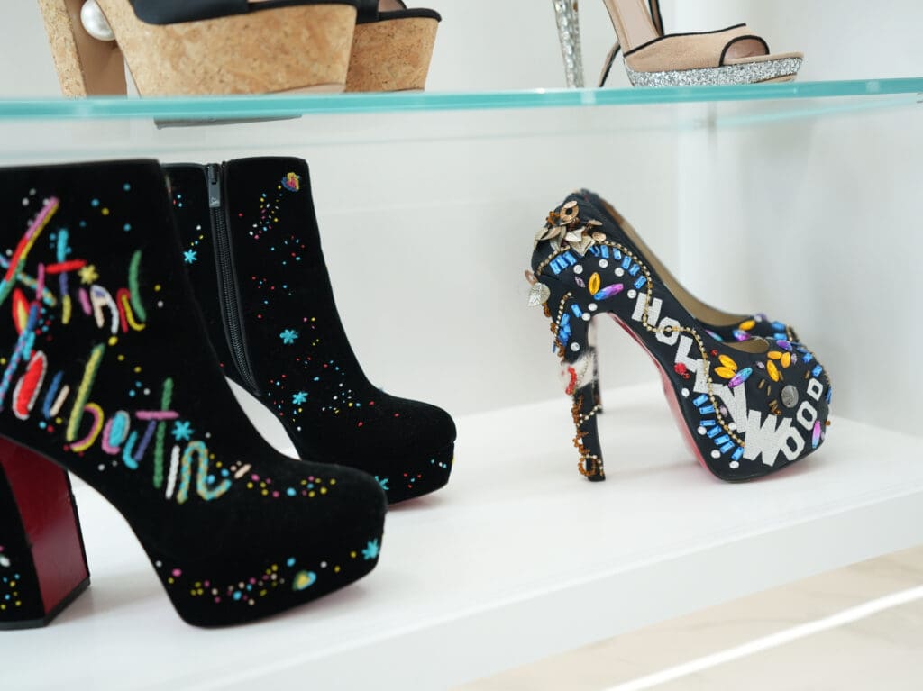 The Christian Louboutin Movida Total Embroidered Red Sole Booties and the Christian Louboutin Limited Edition, Highness 160 Pump share a shelf in the Roemer closet.