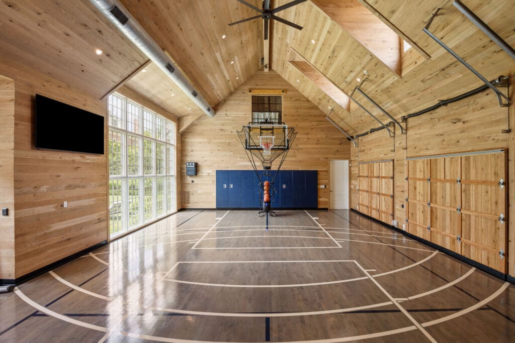 This house's striking three-car garage also functions as a sport court or gym, with beautiful wood paneling, and a gym floor with both basketball and pickleball courts. (Photo by Full Package Media / Compass)