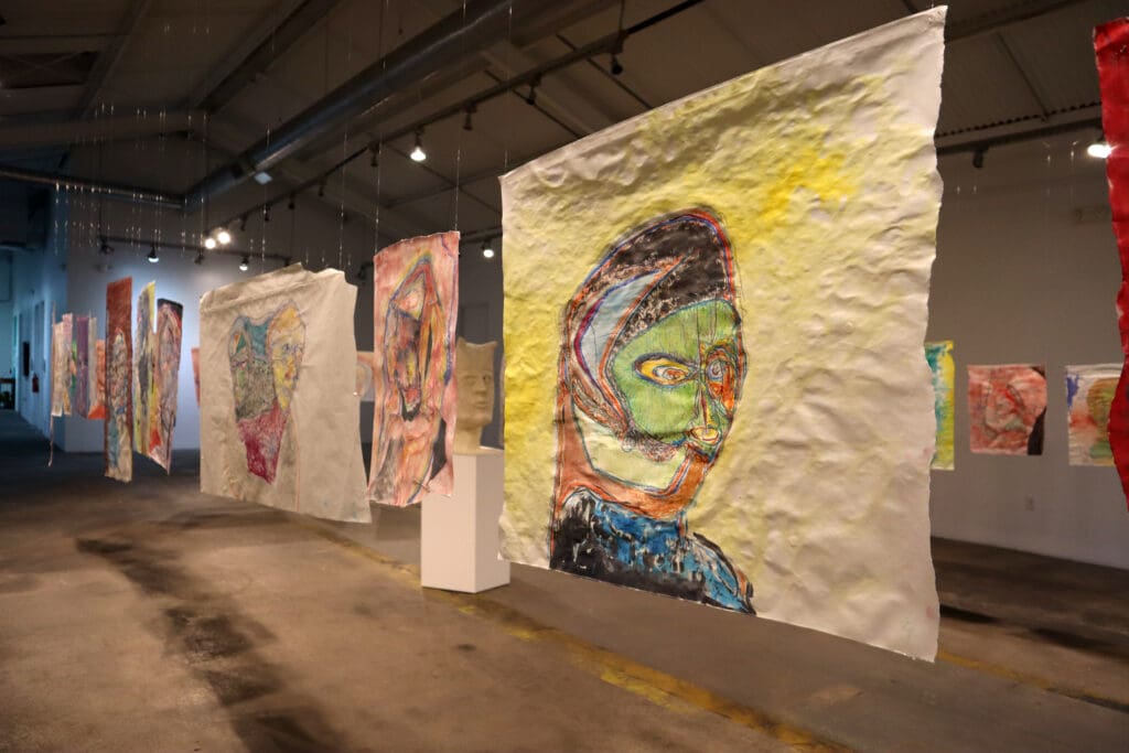Justin Earl Grant's portraits of colorful, distorted faces from hung at Sabine Street Studios. (Image courtesy of the artist). 