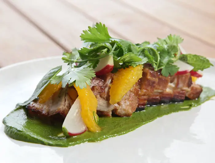 Bacon Steakie with pork belly cured and roasted, herb purée citrus radishes, and serrano