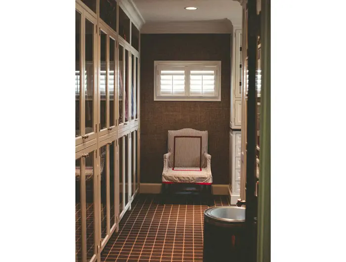 The front wing of Powers' closet– cabinets are glass and walls covered with a rich hue of grasscloth