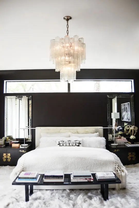 Farrow & Ball Tanner’s Brown No. 255 gives the master bedroom a subdued and moody feel. Custom white-linen headboard. Vintage Chinese chests with engraved brass dragons, which Clair purchased at an estate sale. Provocative black-and-white photo by L. A. fashion photographer Tatiana Gerusova from Gallerie Noir. Vintage Venini Italian chandelier. White Kidassia goat-fur rug.