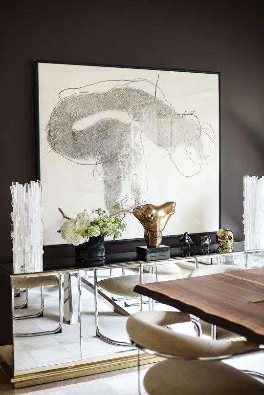 In the dining room, Nadara Goodwin’s Sea Mouth with Hook hovers above a vintage Mastercraft mirrored console from Give and Take. Two vintage Cleo Renault Lucite column lamps flank a bronze sculpture by Nigel Richie from the family collection of Clair’s husband, David.
