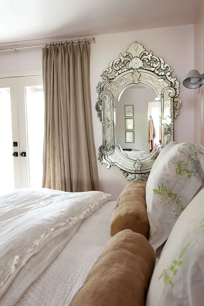The master bedroom has pale-pink walls and ceiling, natural washed-linen curtains and an antique Venetian mirror. Bed linens are Yves Delorme and Bella Notte, both from Kuhl-Linscomb.