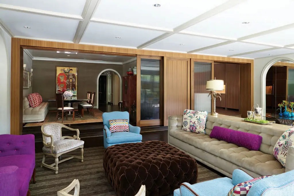 The elevated dining room is separated from the family room by sliding doors made from European walnut and glass, a Paul Garzotto design. Walls upholstered in indoor/outdoor velvet from Holly Hunt.