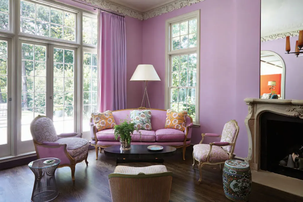 The living room has its original ornate plaster molding and marble fireplace. Inherited Louis XV pieces and antiques from Embree & Lake mix with modern elements, including the husband’s Platner side table.