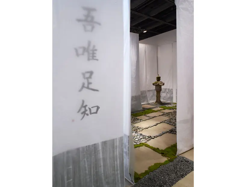 Calligraphy upon fabric scrims, rocks, moss, stepping stones, and a single garden ornament mark the entrance to "I Am Content with What I Lack."