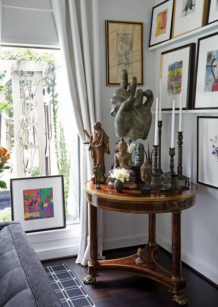 An Empire-era table holds a collection of 16th-century Turkish candlesticks, a 17th-century French saint and a Thai Buddha. Above, a 16th-century Italian pencil drawing and works by Mirò and Chagall. The artwork in the window is a hand-colored invitation to a party at Radio City Music Hall, on which Andy Warhol drew hearts; a gift to Smith’s mother, it reads, “To Jane, love Andy.”
