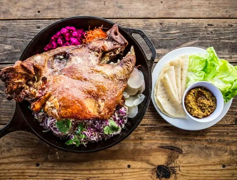 The half a pig head at The Hay Merchant is served with lettuce cups, tortillas, kimchi salsa and pickled vegetables (Photo by The Hay Merchant). 