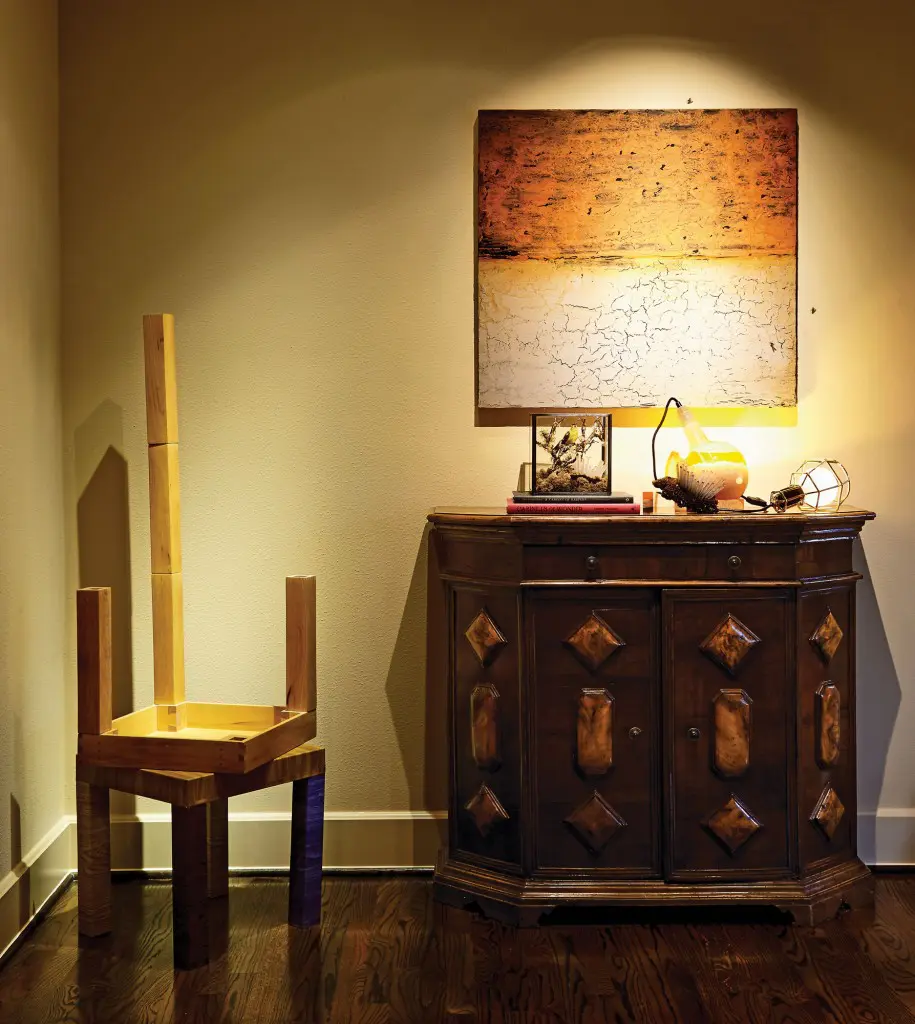 Vernon Fisher’s depiction of an African sunset with parched desert includes freeze-dried flies with thin bronze legs, which the owner of the artwork can place at will. Santiago Cucullu’s Stacked Tables with One Extra Leg, 2001, through Barbara Davis Gallery. German light fixture is filled with lard that creates a glow when heated. Antique Italian console with burl-wood inlay.