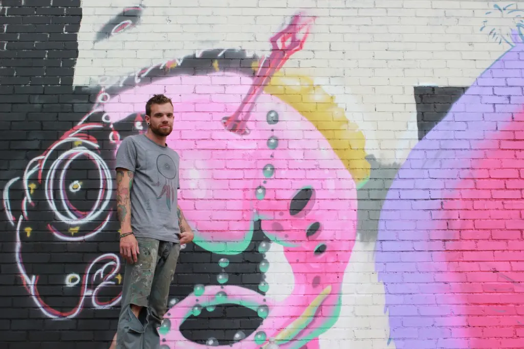 Tarboxx2, a street artist based in Houston, stands with his mural at Capitol Street Fabrication and Gallery. (6697 Capitol)
